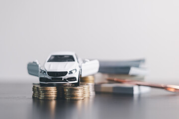 White car model with open door surrounded by stacked coins, symbolizing auto loan, car finance, investment, insurance, and savings concept on a clean minimal background. car finance