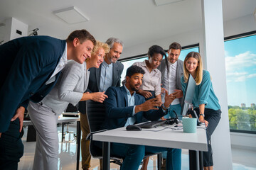 Diverse business team huddling around a computer, discussing data and collaborating on a project, showcasing successful teamwork and modern office cooperation