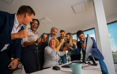 Diverse business team cheering together, expressing excitement and happiness while celebrating a major achievement or project success in a modern office environment