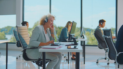 Diverse team of customer service representatives wearing headsets and working on computers in a bright modern office, actively assisting clients with support inquiries