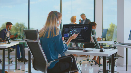 Woman wearing headset communicating and analyzing data on a computer screen displaying a global map and futuristic interface, working in a contemporary, open-plan office environment