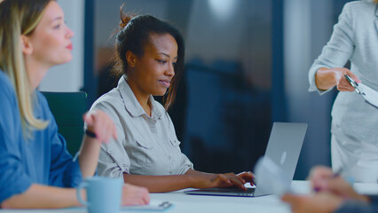 Diverse businesswomen attending an important corporate meeting in a modern office setup, focusing on collaboration, digital communication, and professional development during a productive session