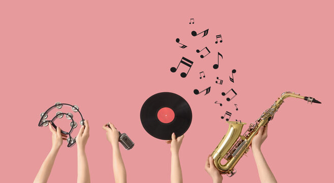 Hands with musical instruments, microphone and vinyl disc on pink background