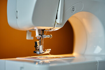 Close-up view of sewing machine needle and presser foot with thread. Concept of sewing and handmade craft