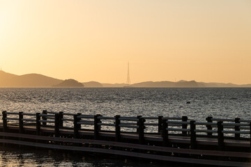 Obraz premium idyllic seascape with island, pylon and pier during sunset