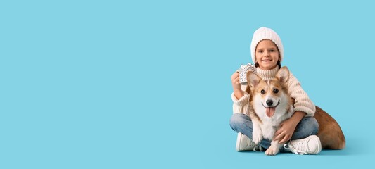 Cute smiling girl with dog and cup of hot chocolate on blue background with space for text