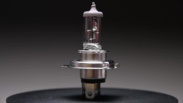 Halogen car bulb with H4 base. Rotates on a black background. Car bulb for lighting while driving.