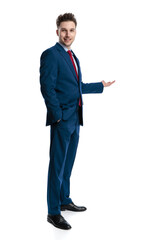 side view of happy young man presenting to side and smiling