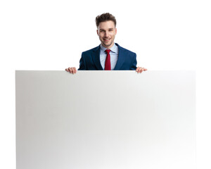 handsome young man in suit holding and presenting empty billboard
