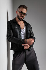 confident cool man with sunglasses leaning on a wall and looking forward