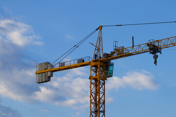 Bright Yellow Tower Crane Against a Blue Sky with White Clouds