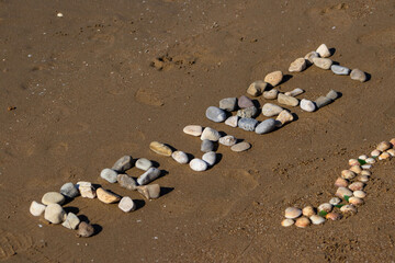 The Russian Word 'Hello' Spelled Out with Beach Pebbles on Sandy Ground