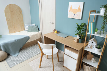 Interior of stylish children's room with modern workplace, shelving unit and bed near turquoise wall