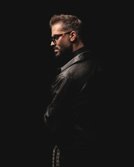 side view of cool fashion man in black leather jacket looking to side