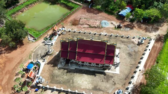The image sequence shows an aerial view of a construction site of a traditional building with a red roof, surrounded by a boundary wall made of concrete blocks