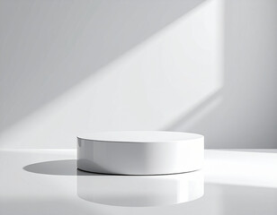 A minimalist white cylinder pedestal casting a shadow on a white wall with diagonal light.