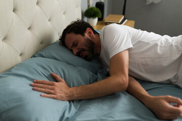 Emotional man crying in bed after breakup