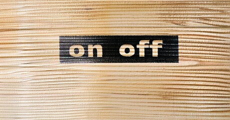 Wooden surface displays on off text. Black rectangle contrasts light wood grain. Simple design, clear labeling, functional aesthetic.