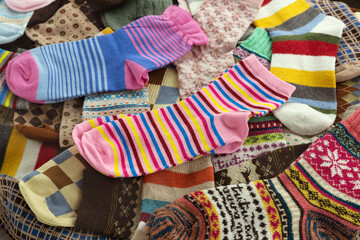 Multicolored socks are folded into a large pile. Lots of socks for fall and winter.