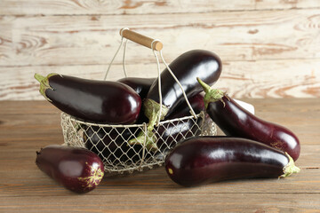 Basket with fresh eggplants on wooden background