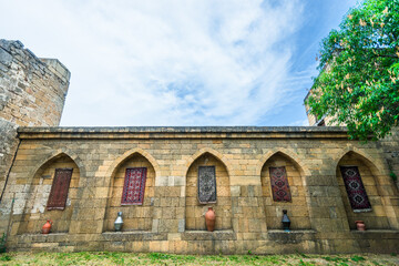 Naklejka premium The inner side of the old fortress wall of the Naryn Kala citadel decorated with carpets and jugs. Dagestan