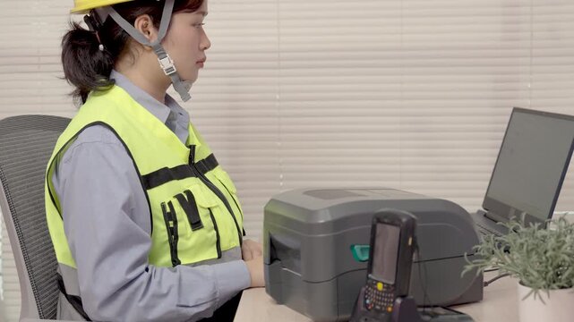 Beautiful Asian woman uses a laptop or notebook to print bar code stickers on a bar code printer.