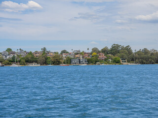 Fototapeta premium 11 October 2025 Residential Houses and apartment buildings on Parramatta River Sydney Harbour on a warm spring cloudy overcast day in Sydney NSW Australia
