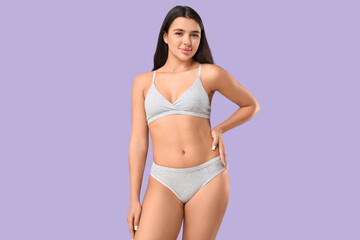 Fototapeta premium Beautiful young woman in underwear on lilac background