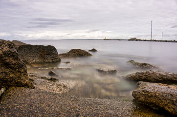 Misty Long Exposure Seascape with Rocky Shoreline and Industrial Port Pier