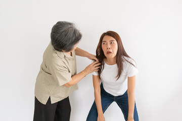 Asian Thai elderly mother scolding and shaking shoulder daughter crying funny face isolated over white wall.