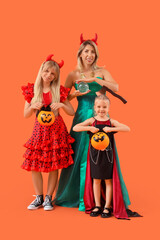 Happy girls with their grandmother dressed for Halloween on orange background