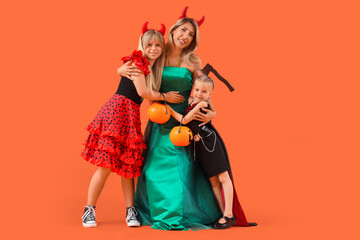Happy girls with their grandmother dressed for Halloween hugging on orange background