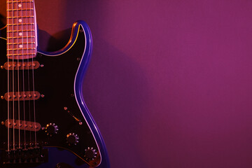 Modern electric guitar on purple background
