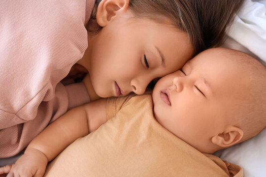 Cute little girl with her baby brother sleeping on bed, closeup - Powered by Adobe