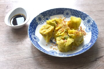 steamed yellow Chinese dumpling filling mashed pork and shrimp or dim sum topping parsley on plate dipping sour soy sauce 