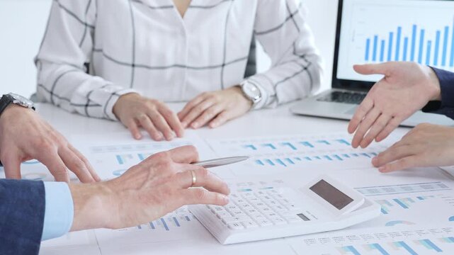 Business people professionals or accouters analyzing financial reports, charts and graphs on laptop and paper, using calculator to discuss strategy, budgeting and teamwork decisions