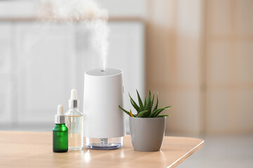 Air humidifier with essential oils and plant on table in bathroom, closeup