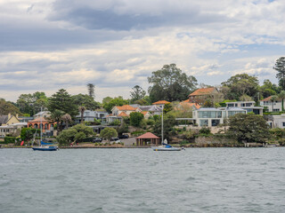 Fototapeta premium Residential Houses and apartment buildings on Parramatta River Sydney Harbour on a warm spring cloudy overcast day in Sydney NSW Australia