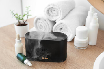 Modern air humidifier with essential oils on table in bathroom, closeup
