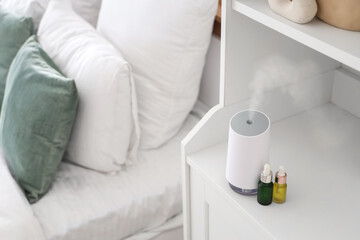 Air humidifier with essential oils on shelf in bedroom, closeup