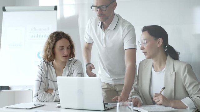 Business team collaborating and analyzing data on a laptop during a dynamic office meeting, uniting efforts to reach shared objectives and drive successful outcomes together