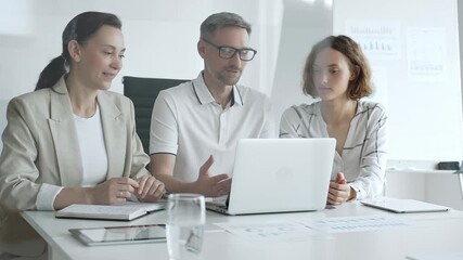 Professional team analyzing data on laptop, sharing insights during collaborative office meeting, highlighting workplace synergy and strategic planning - Powered by Adobe