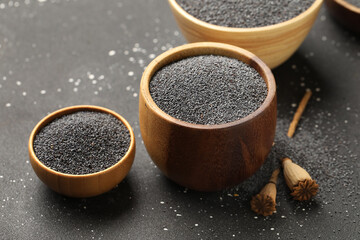 Wooden bowls with poppy seeds on black background, closeup