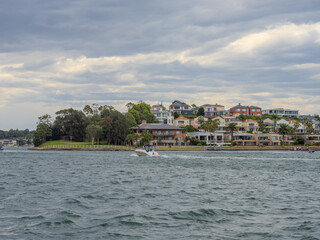 Obraz premium Residential Houses and apartment buildings on Parramatta River Sydney Harbour on a warm spring cloudy overcast day in Sydney NSW Australia