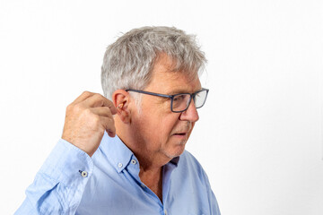 sixty years old man with blue shirt inserting his hearing aid