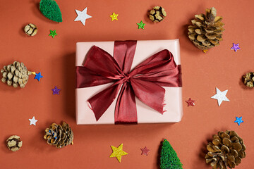 Elegant Pink Gift Box With Burgundy Ribbon Surrounded By Pinecones And Festive Stars