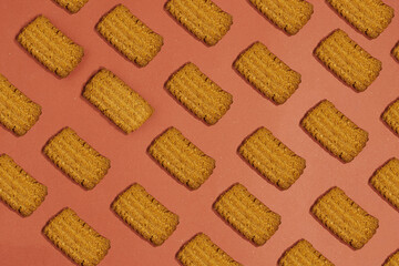 Golden Brown Rectangular Cookies Arranged in a Diagonal Pattern on a Pink Background