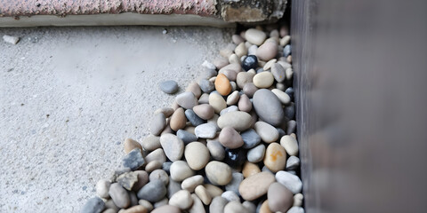 Pebbles and small rocks tumbling through a narrow gap between a concrete surface and a metal edge.