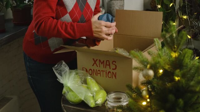 Christmas food donation, charity concept. Volunteer collecting food supplies in donation box.