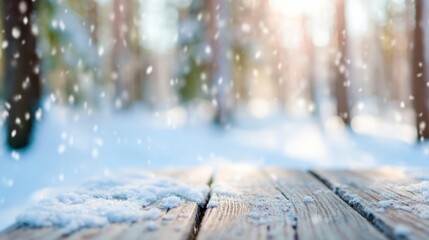 Soft snowflakes drift down onto a wooden surface in a serene winter forest. The sunlight filters through tree branches, creating a warm glow.